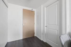 Ein Flur mit einer Holztür, einer weißen Tür und einem grauen Stuhl.