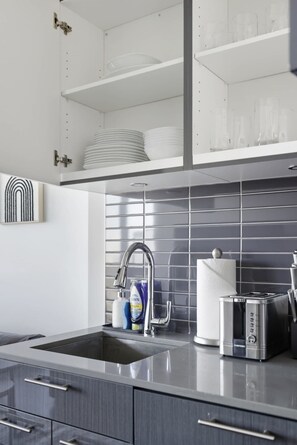 A modern kitchen with a stainless steel sink, a toaster, and a dish rack. - Urban 2BR Suite near Yonge-Dundas | Private Balcony | Parking Available (Toronto)