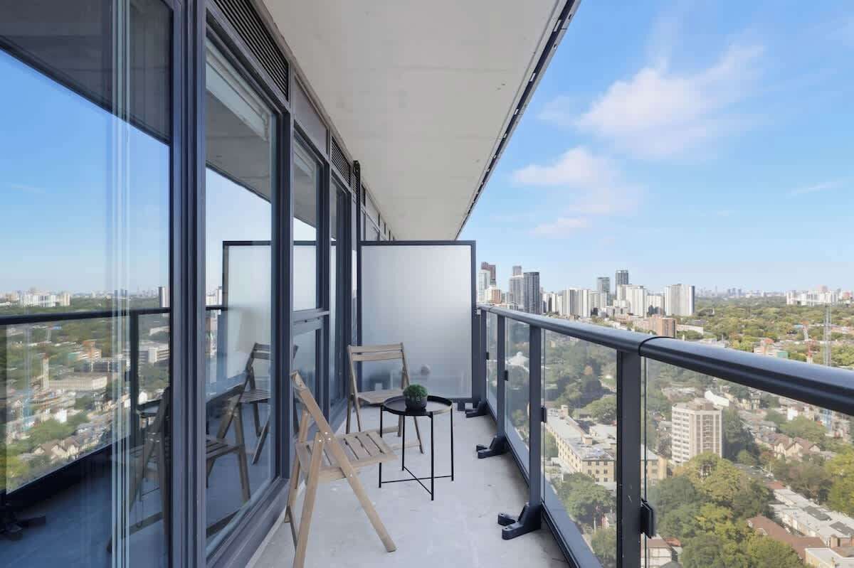 A balcony with a city view, a small table with a plant, and two chairs.