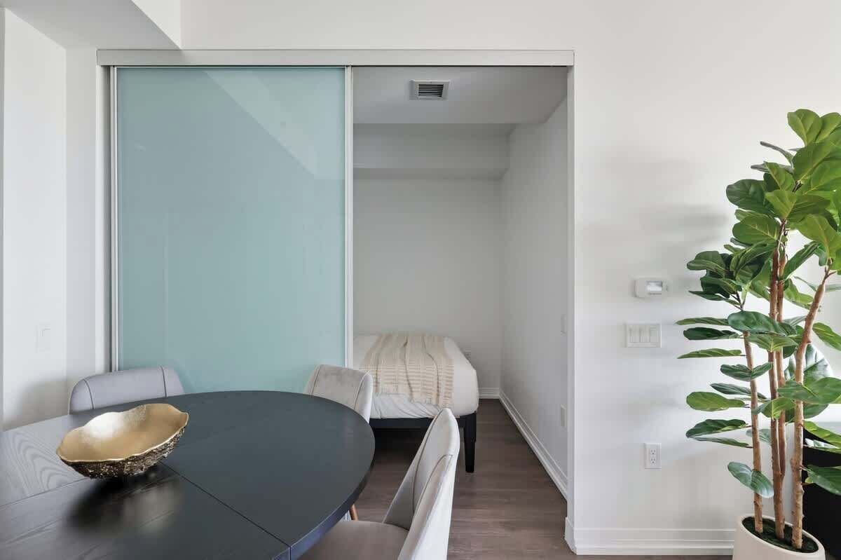 A modern room with a round table, a bench, a bed, and a potted plant.