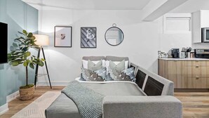 Un dormitorio moderno con cama, mesita de noche, lámpara y una planta en maceta.
