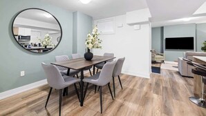 Una sala moderna con comedor, un espejo redondo y un televisor de pantalla plana.