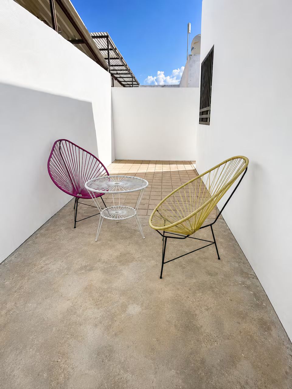 A small outdoor patio with two wireframe chairs and a round table.