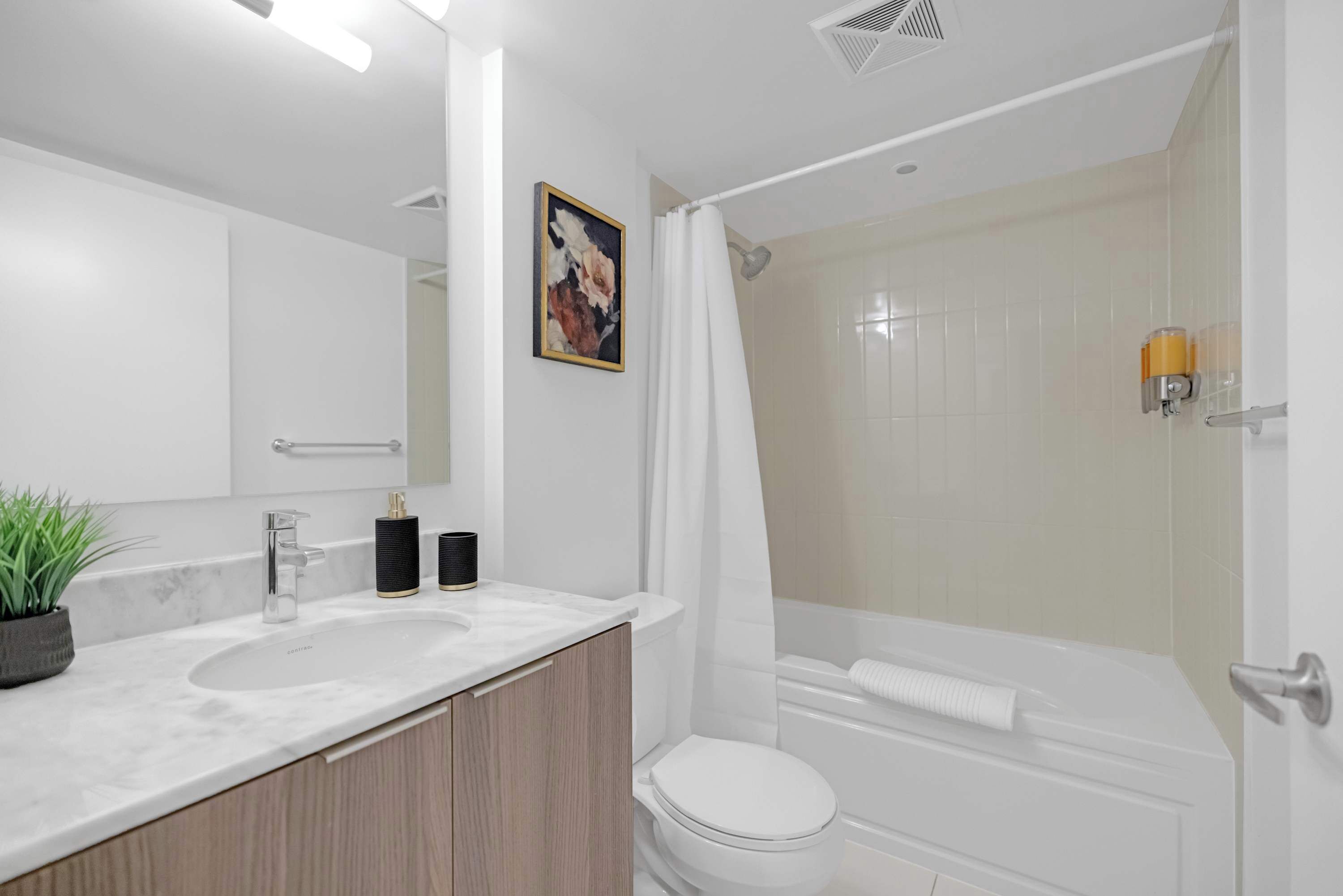 A modern bathroom with a white sink, a toilet, and a shower area.