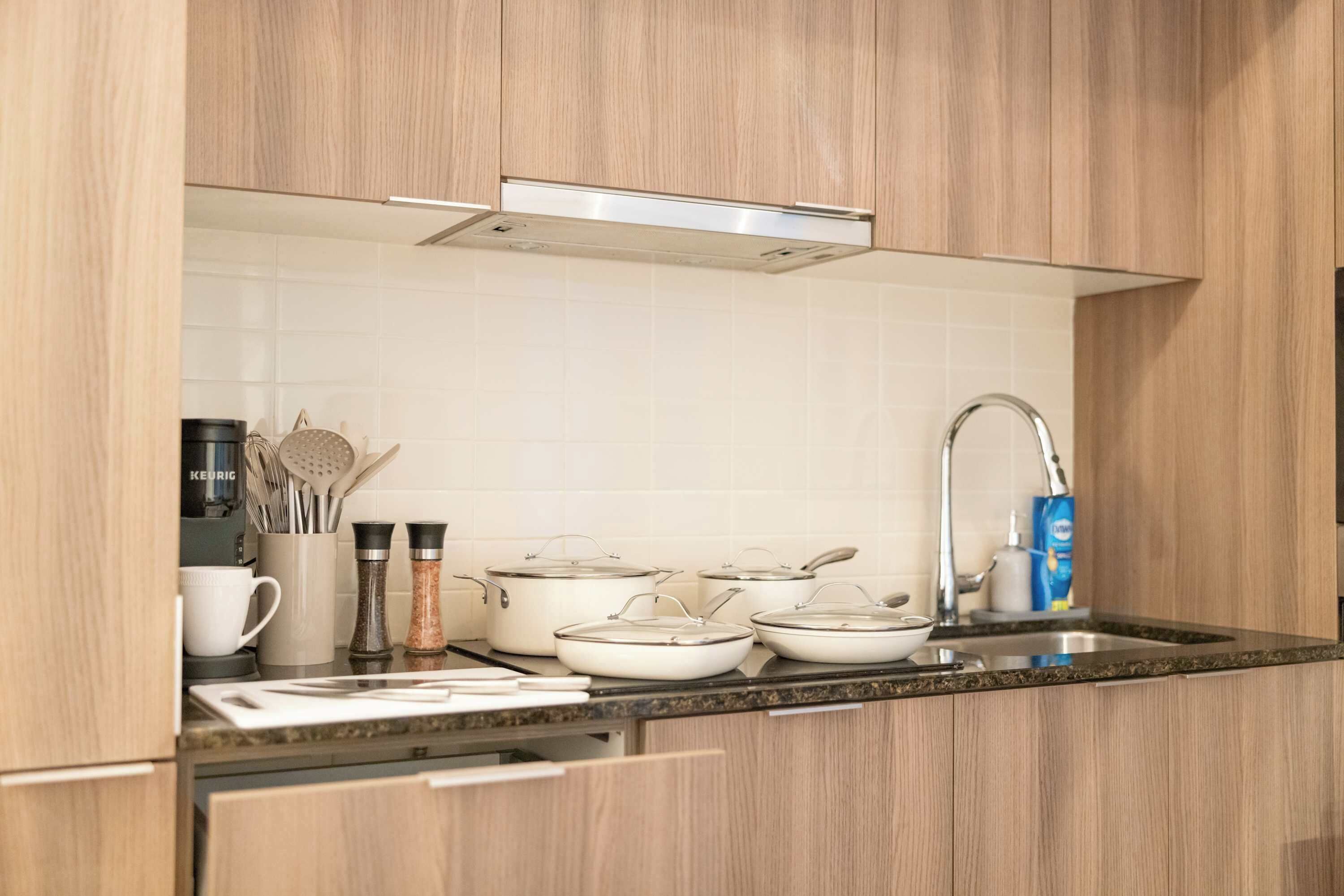 Una cucina moderna con mobili in legno, un lavello in acciaio inossidabile e diversi utensili da cucina.