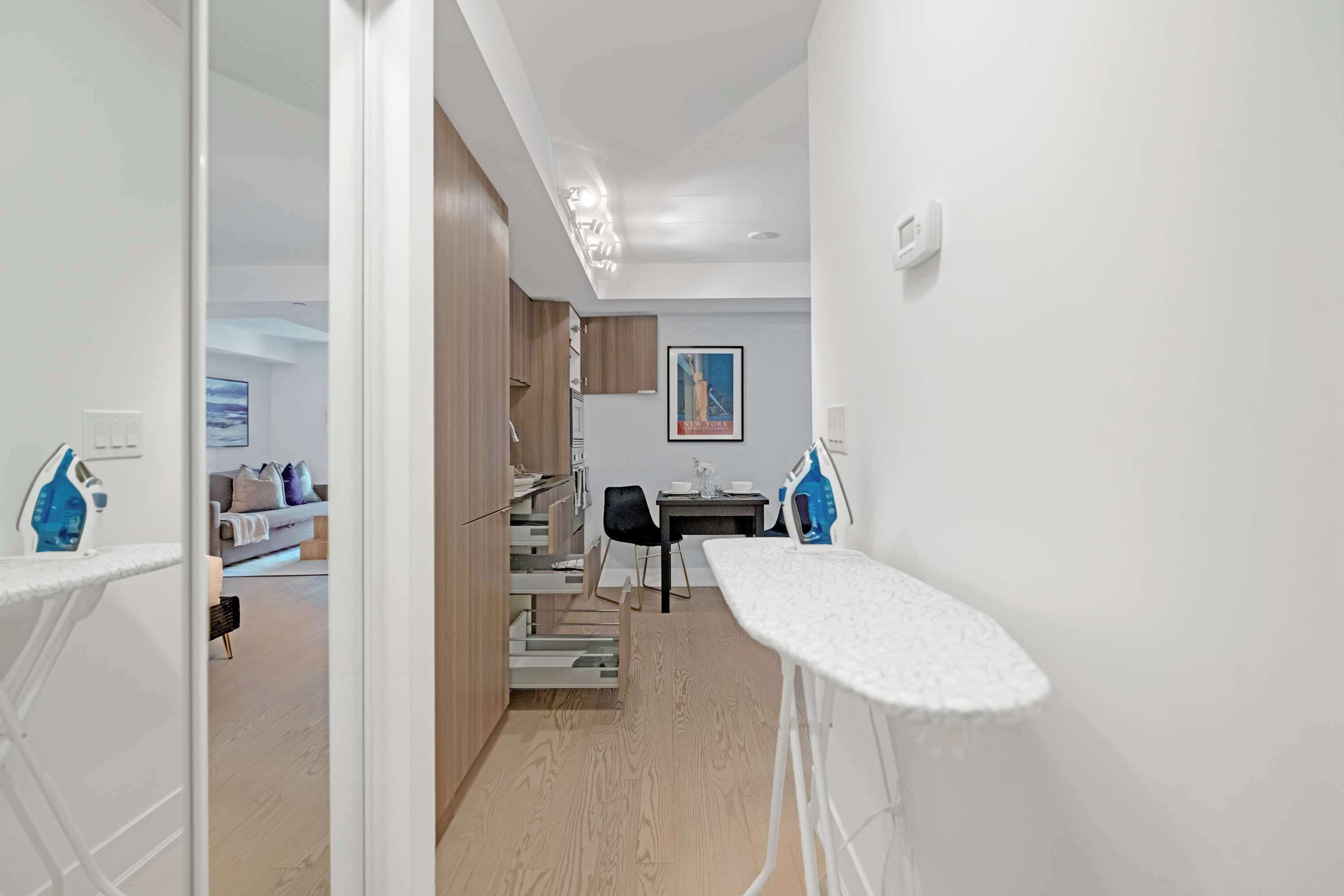 A modern kitchen with a dining area, featuring a built-in oven, a sink, and a dining table with chairs.