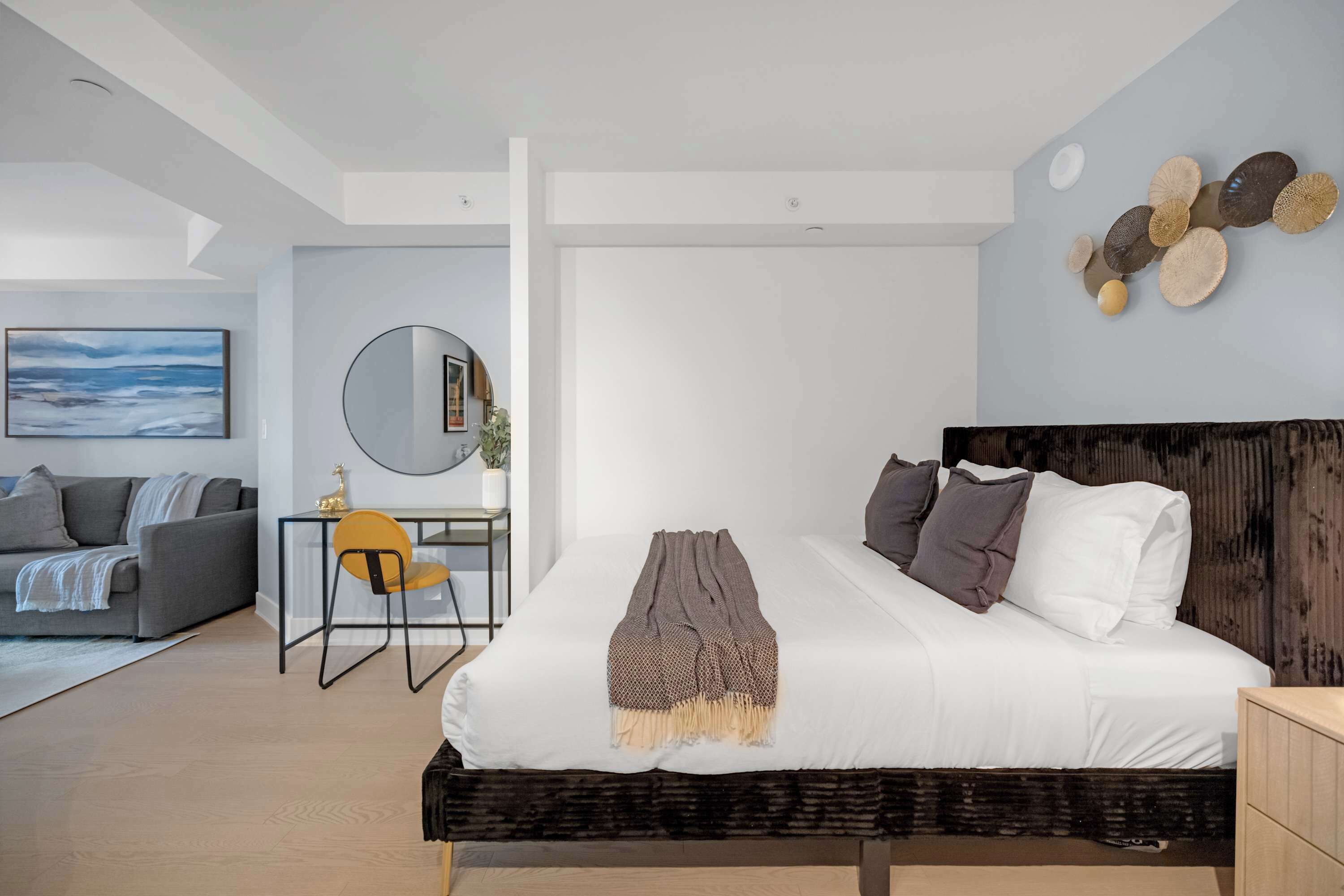 A modern bedroom with a bed, a desk, and a sofa.