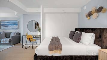 A modern bedroom with a bed, a desk, and a sofa.