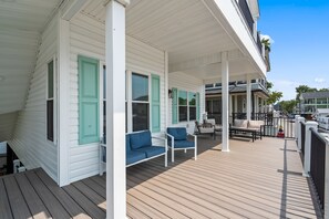 A covered porch with wooden flooring, white railings, and blue outdoor furniture. - Driftwood Dreams at Ocean Lakes - w Golf Cart (Myrtle Beach)
