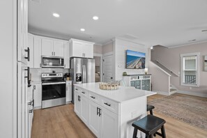 A modern kitchen with white cabinetry, stainless steel appliances, and a central island. - Driftwood Dreams at Ocean Lakes - w Golf Cart (Myrtle Beach)