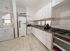 Una cocina con armarios blancos, un refrigerador, una estufa y un ventanal.
