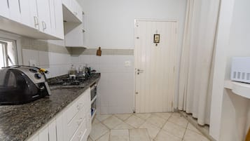 Uma cozinha com armários brancos, bancada de granito, fogão e micro-ondas.