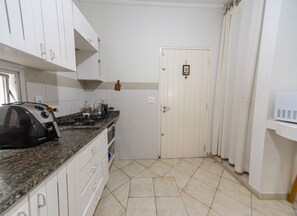 Uma cozinha com armários brancos, bancada de granito, fogão e micro-ondas.