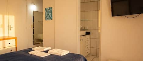A hotel room with a bed, a wardrobe, a bathroom, and a TV.