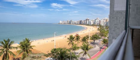 A coastal cityscape with a beach, palm trees, and high-rise buildings.