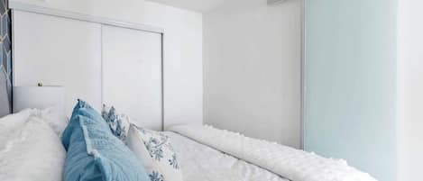 Une chambre à coucher avec un lit, des oreillers, une armoire et une porte coulissante.