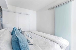 Ein Schlafzimmer mit einem Bett, Kissen, einem Kleiderschrank und einer Schiebetür.