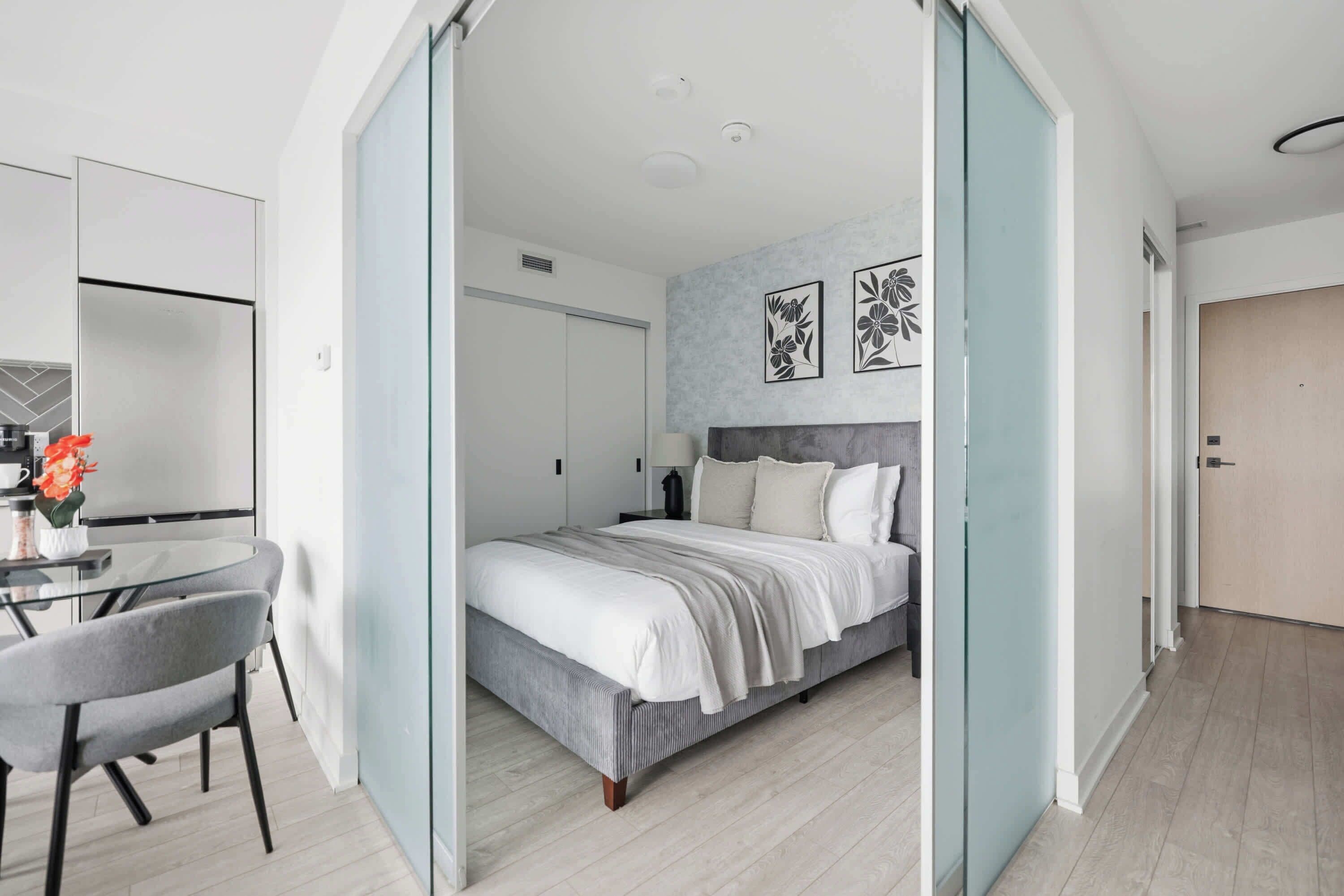 Une chambre à coucher moderne, avec un lit, une table de chevet et une vue sur la pièce adjacente.