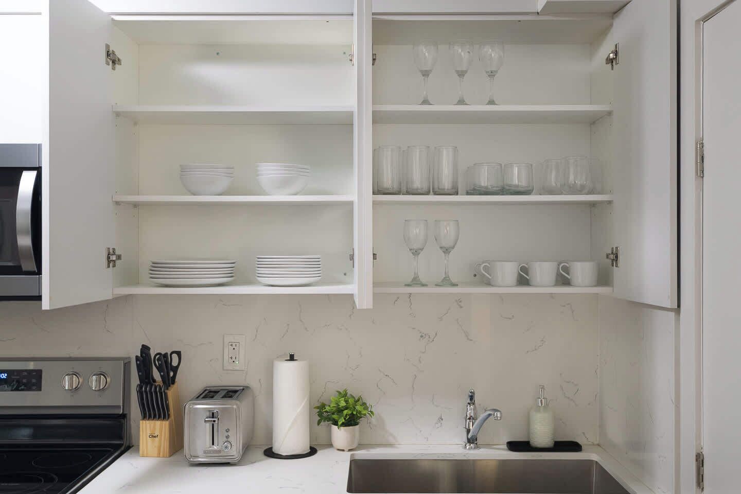 A kitchen with white cabinets, a toaster, a sink, and a marble backsplash.