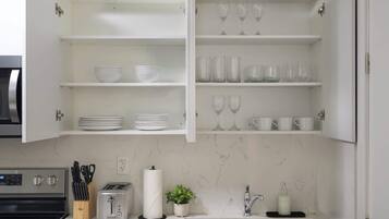 A kitchen with white cabinets, a toaster, a sink, and a marble backsplash.