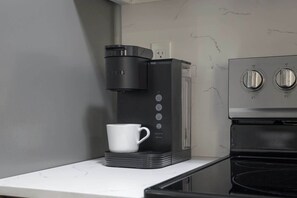 Eine Küche mit Kaffeemaschine, einer weißen Tasse und einem Herd.