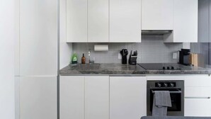 Une cuisine moderne avec des armoires blanches, un comptoir en granit, un four encastré et un évier en acier inoxydable.