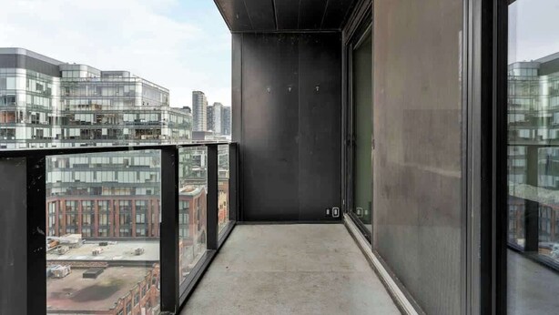 Un balcon offrant une vue sur le paysage urbain, avec des bâtiments modernes et un ciel dégagé.