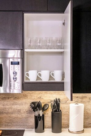 Eine Küche mit Einbauofen, einer Kaffeemaschine und einem Schrank mit Gläsern und Tassen.