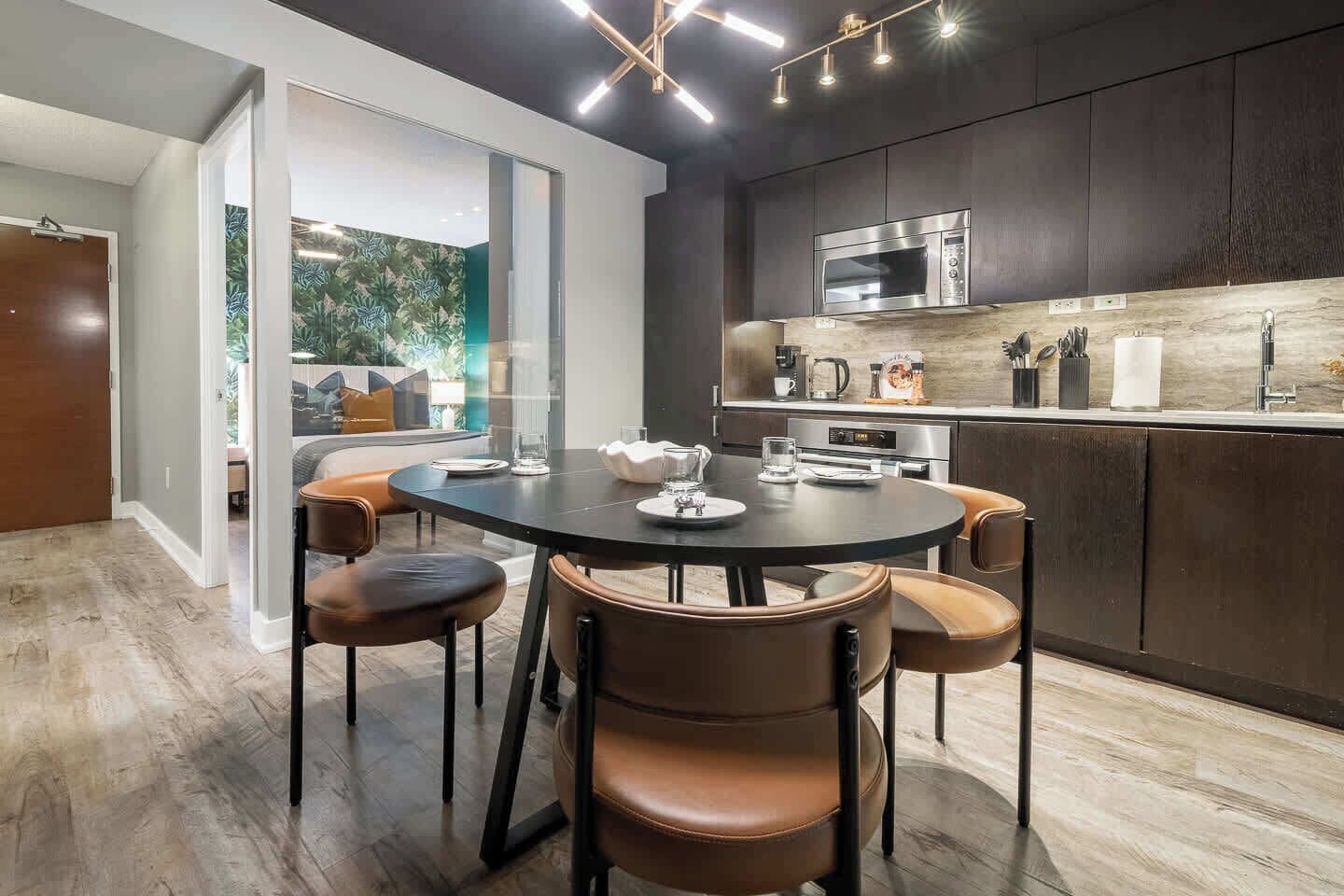 A modern kitchen with a dining area, featuring a round table, chairs, and a built-in oven.