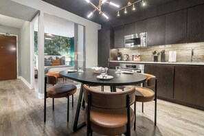A modern kitchen with a dining area, featuring a round table, chairs, and a built-in oven. - Downtown Skyline 2BR+Den Oasis w/ Parking  | Parking Available (Toronto)