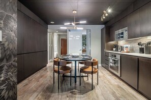 A modern kitchen with dark cabinetry, a central island with seating, and a microwave above the counter. - Downtown Skyline 2BR+Den Oasis w/ Parking  | Parking Available (Toronto)