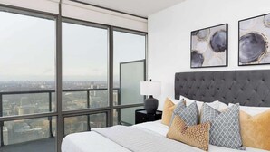 A modern bedroom with a large bed, a nightstand, and two abstract paintings on the wall. - Above the City Designer Sub-Penthouse Oasis (Toronto)