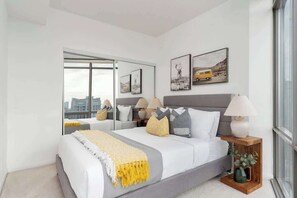 A modern bedroom with a large bed, bedside lamps, a mirror, and artwork on the wall.