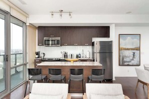 A modern kitchen with dark cabinets, stainless steel appliances, and a central island with bar stools.