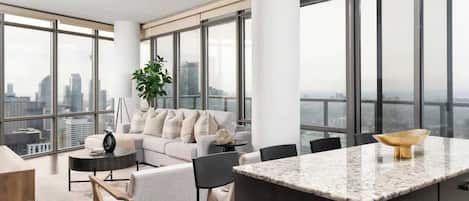 A modern living room with a sofa, chairs, a coffee table, and a kitchen island with a marble countertop.