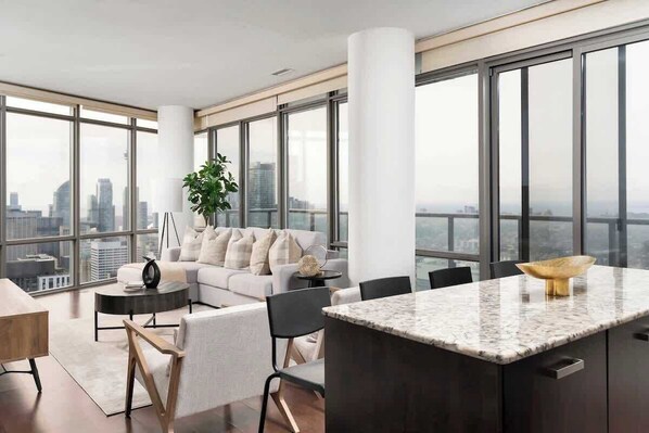 A modern living room with a sofa, chairs, a coffee table, and a kitchen island with a marble countertop.