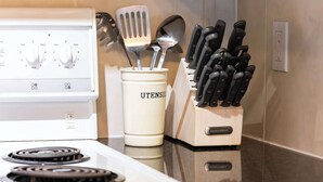 A kitchen with a white stove, a utensil holder labeled 'UTENSILS,' and a knife block with 'TERRIWARE' branding.