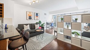 A modern living room with a sofa, coffee table, and a glass partition with a city view.