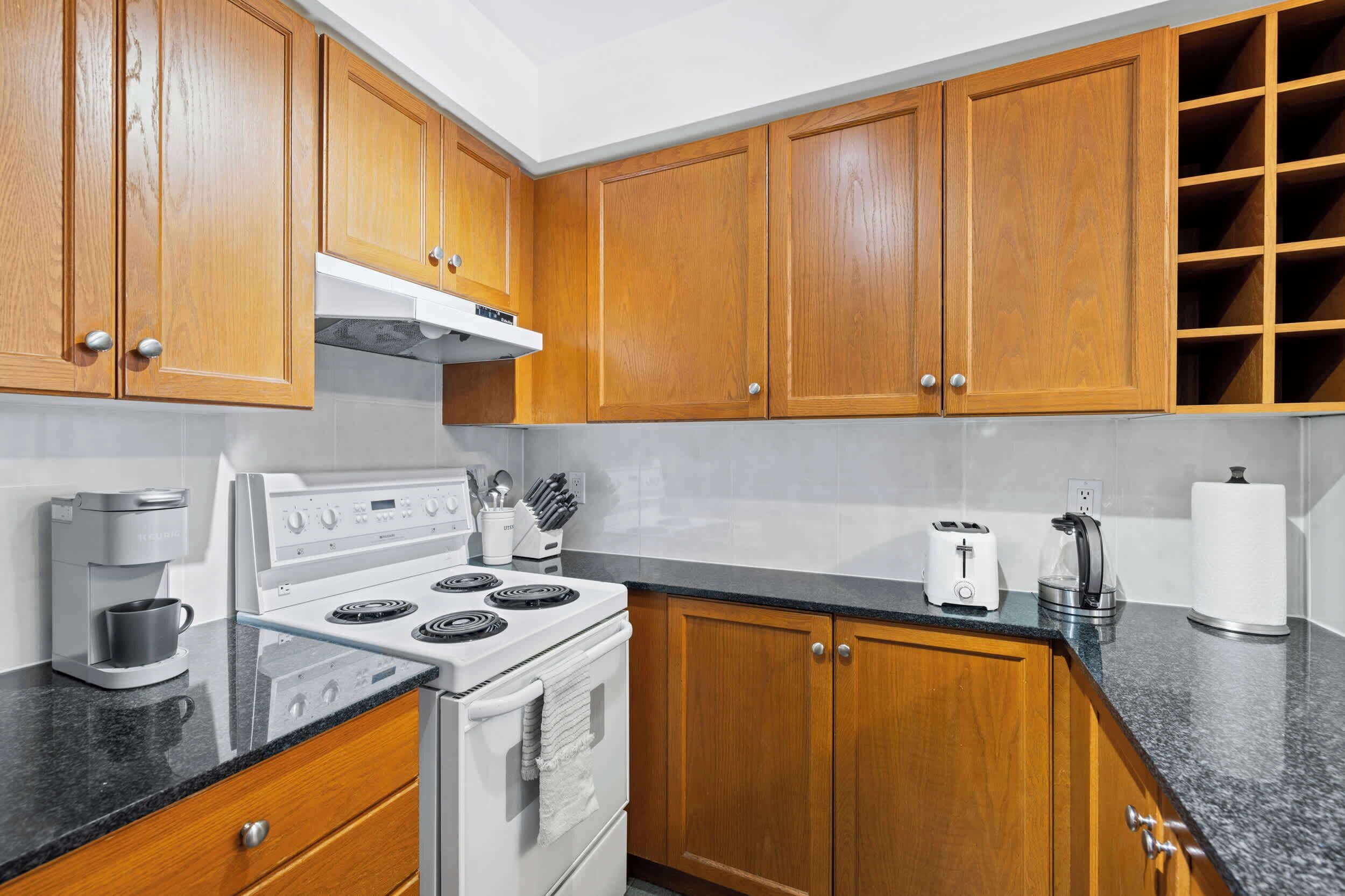 A kitchen with wooden cabinets, a white stove, a coffee maker, and a toaster.