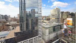 A high-rise building with a modern glass facade, surrounded by other urban structures.