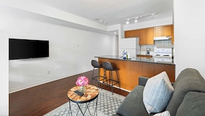 A modern living room with a sofa, a coffee table with a vase, and a TV mounted on the wall.