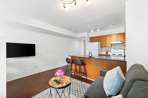 Una sala de estar moderna con un sofá, una mesa de centro con un florero y un televisor montado en la pared.