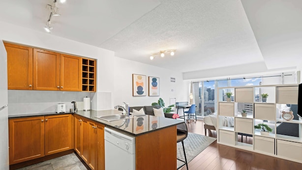 A modern kitchen with wooden cabinets, a built-in dishwasher, and a large island with a sink.