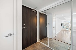 A hallway with a dark wooden door, a sliding glass door, and a tiled floor.