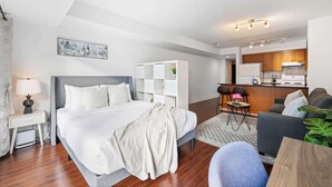 A modern hotel room with a bed, bedside table, lamp, and a view of the cityscape.