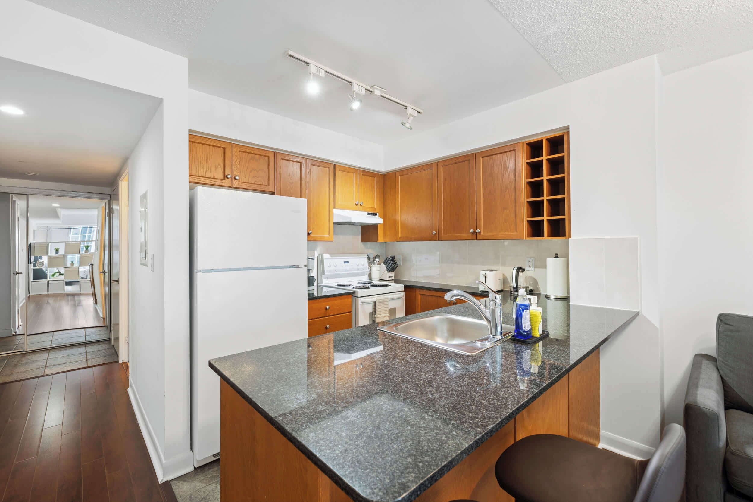 A modern kitchen with wooden cabinets, a stainless steel sink, and a built-in oven.