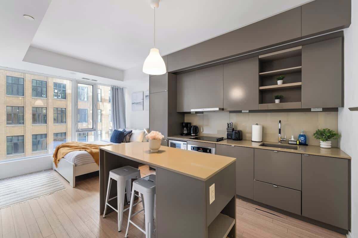 A modern kitchen with a central island, built-in cabinets, and a large window providing natural light.