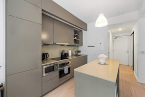 A modern kitchen with built-in appliances, a central island, and a pendant light.