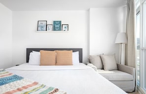 A hotel room with a bed, a sofa, a window with curtains, and wall art. - Cozy Toronto Stay Skyline View | Parking Available (Toronto)
