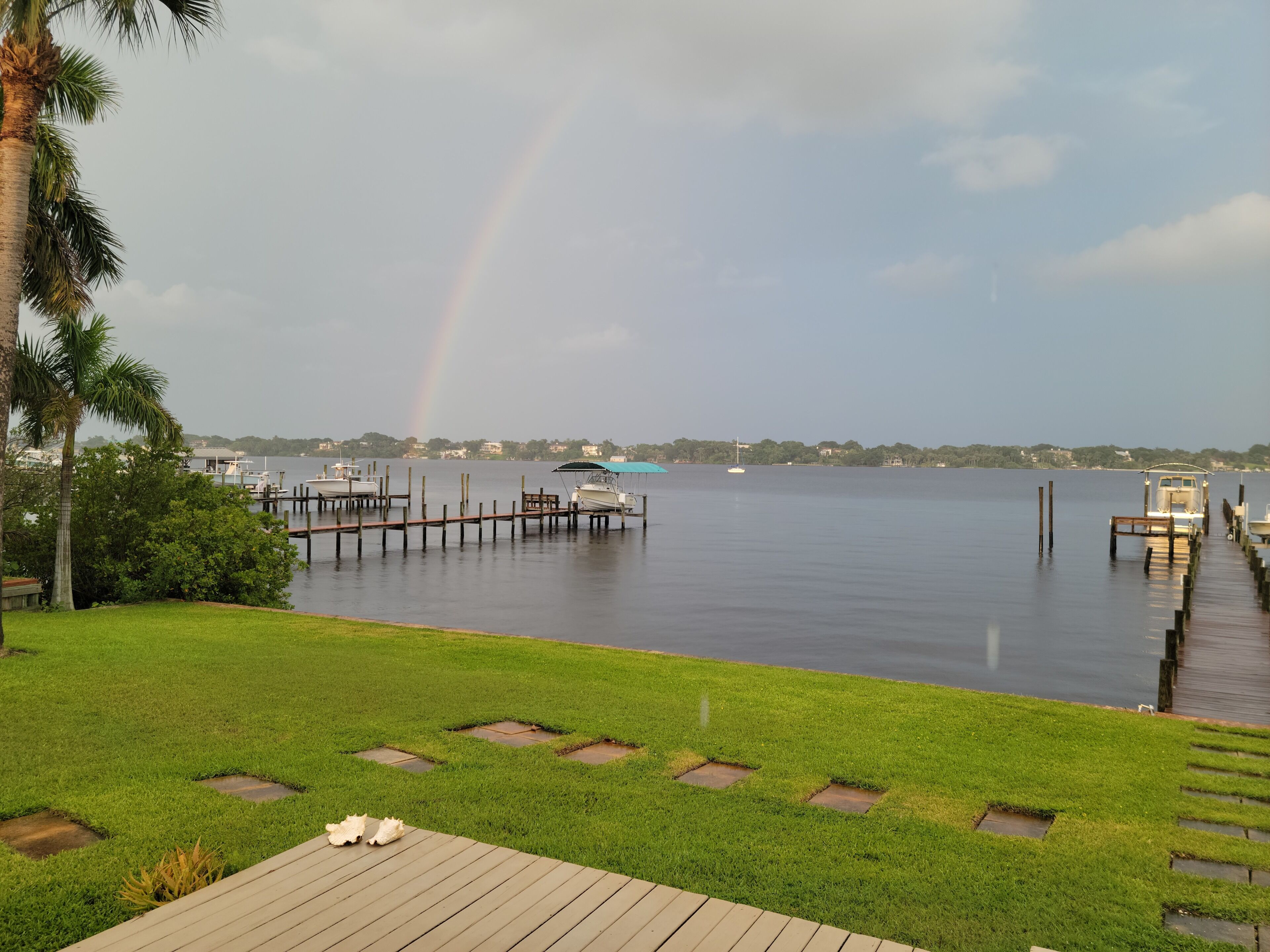 A waterfront property with a dock, boats, and a grassy area.